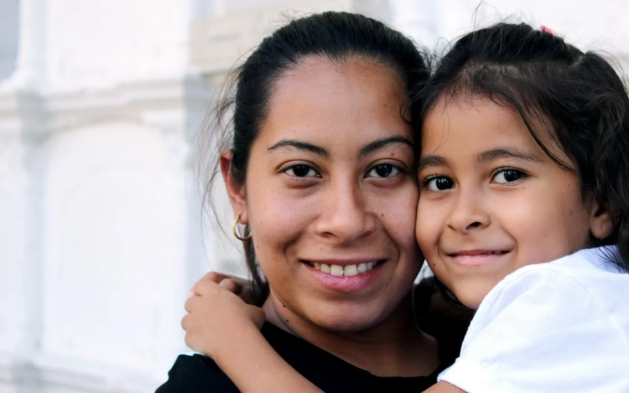 Mãe e filha sorrindo, abraçadas