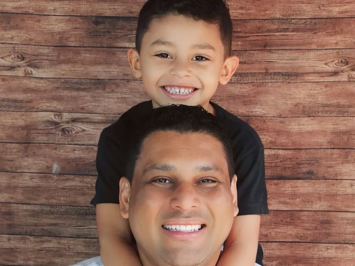 Pai sorrindo com o filho nos ombros